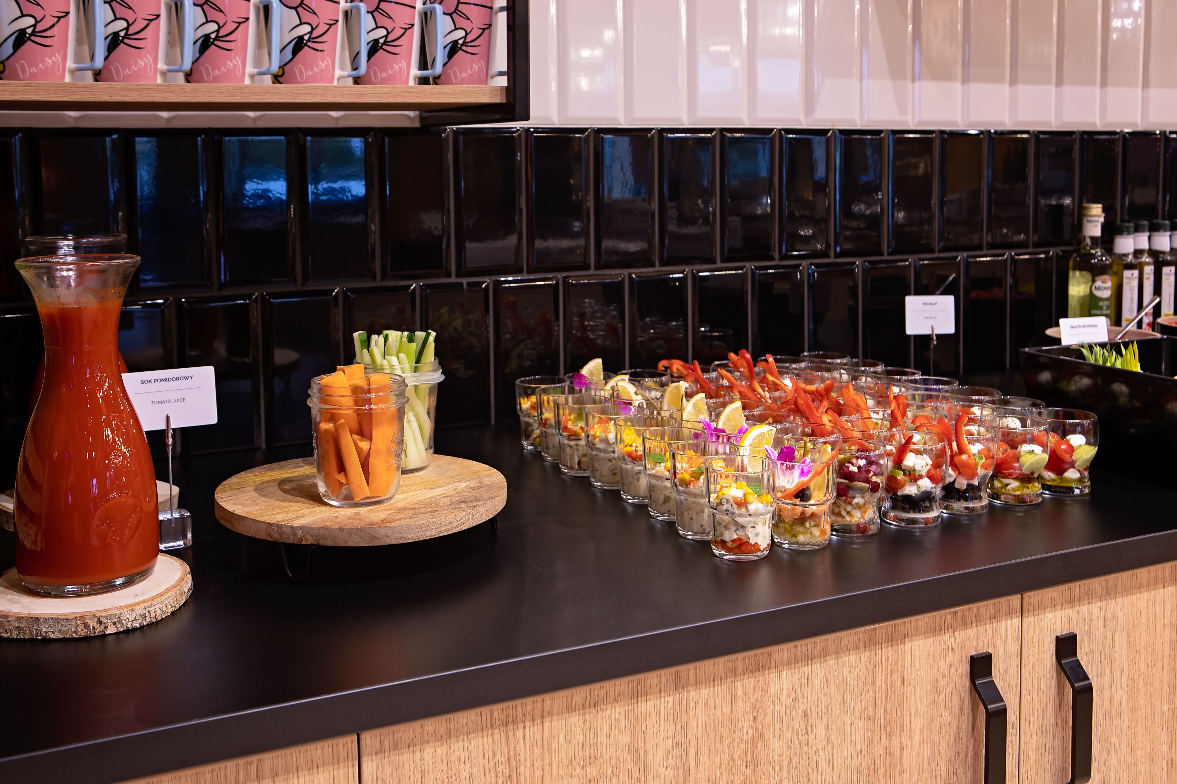Une table de buffet garnie de divers plats et une bouteille de jus de tomate.
