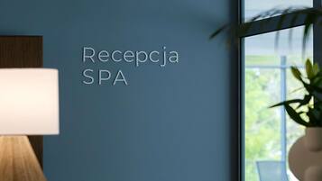 Un área de recepción con un letrero en la pared que dice 'Recepcja SPA' y una lámpara sobre una mesa de madera.