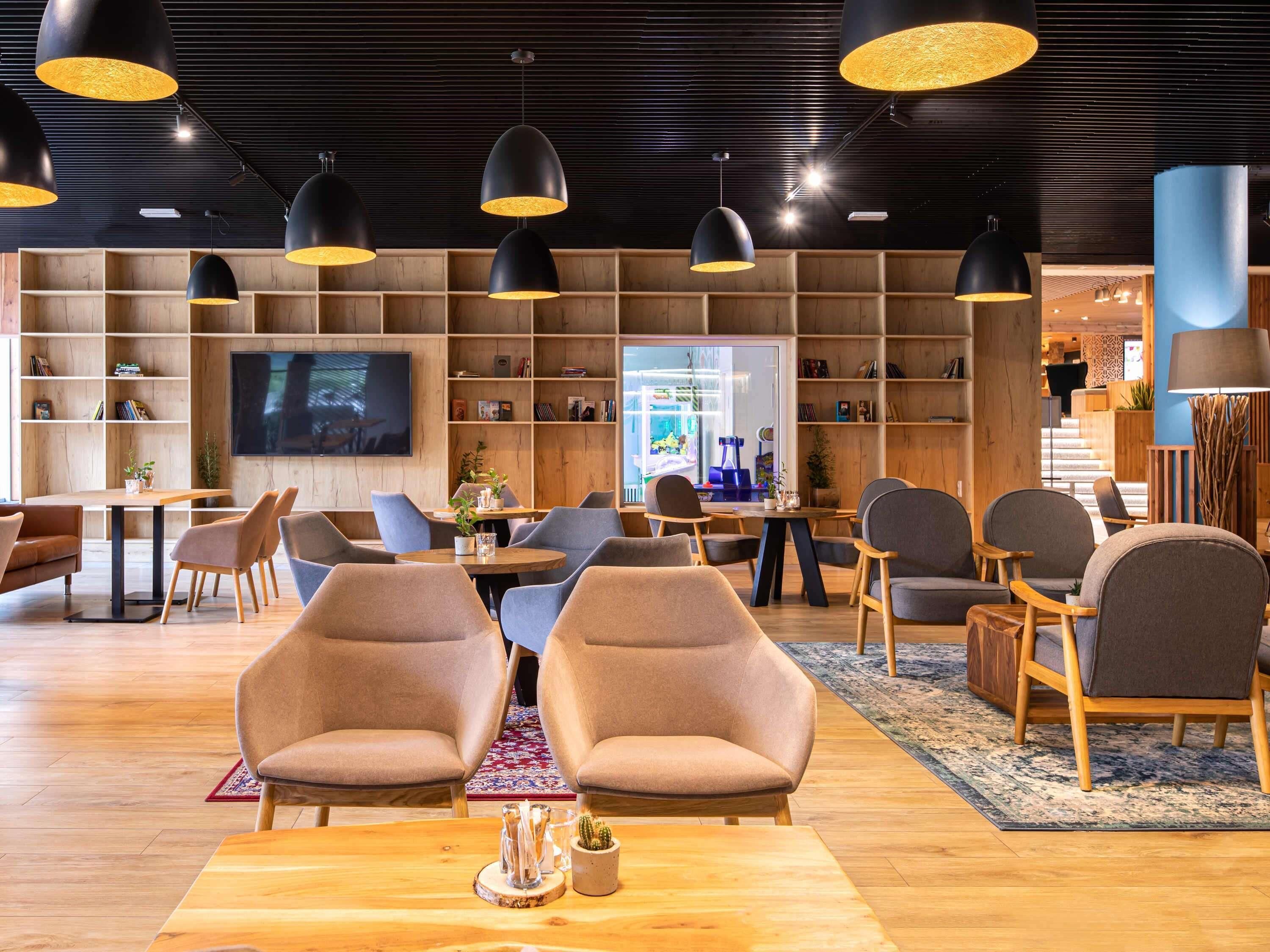 A modern lounge area with multiple seating options, a television, and a bookshelf.