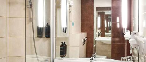 Un baño moderno con cabina de ducha de vidrio, un lavabo espacioso con espejo y un secador de pelo en la encimera.