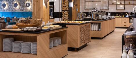 Un buffet proposant une variété de plats, avec des comptoirs de service et une cuisine en arrière-plan.