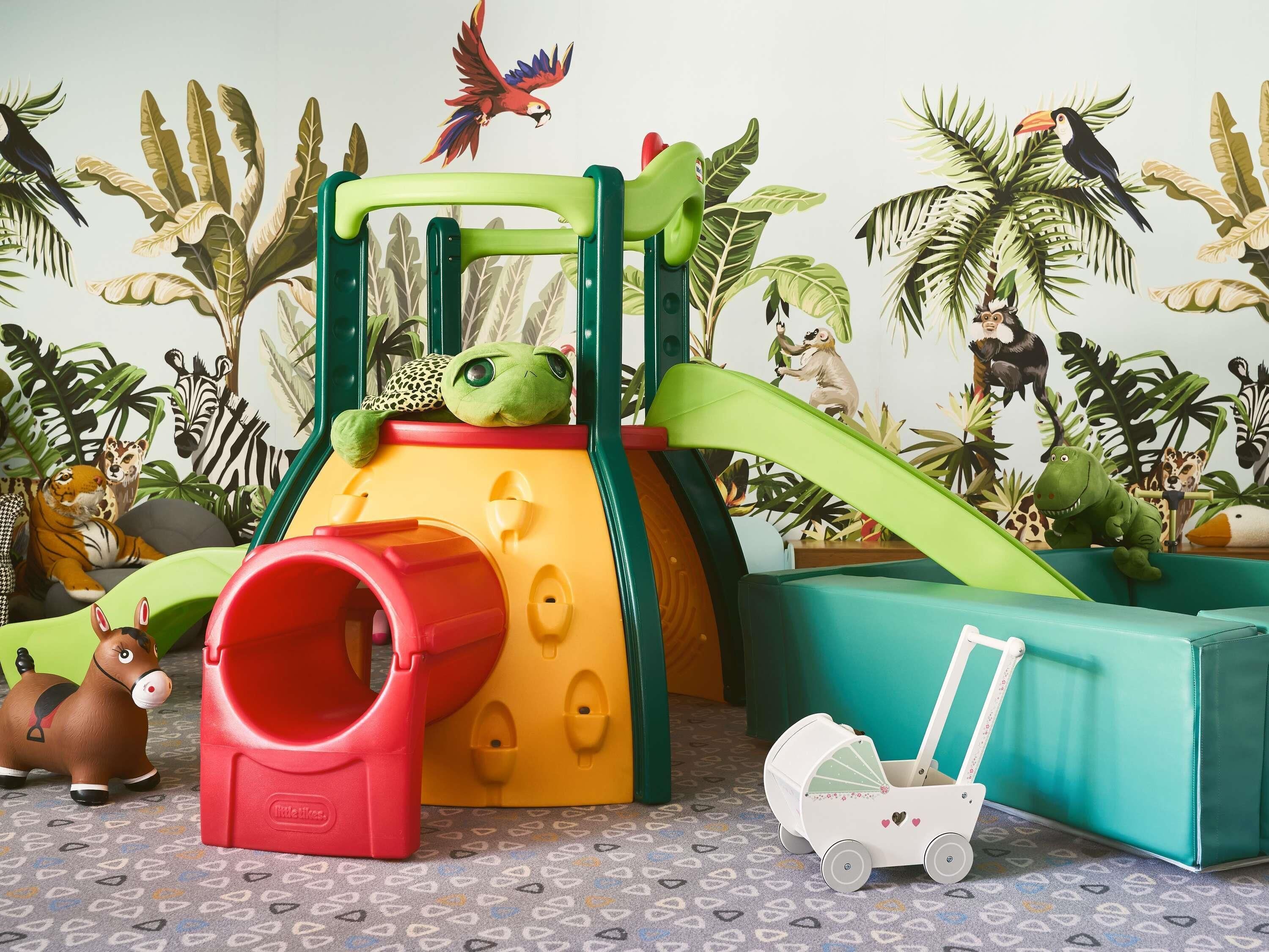 Un espace de jeux pour enfants comprenant un toboggan, une structure d’escalade et diverses décorations sur le thème des animaux.