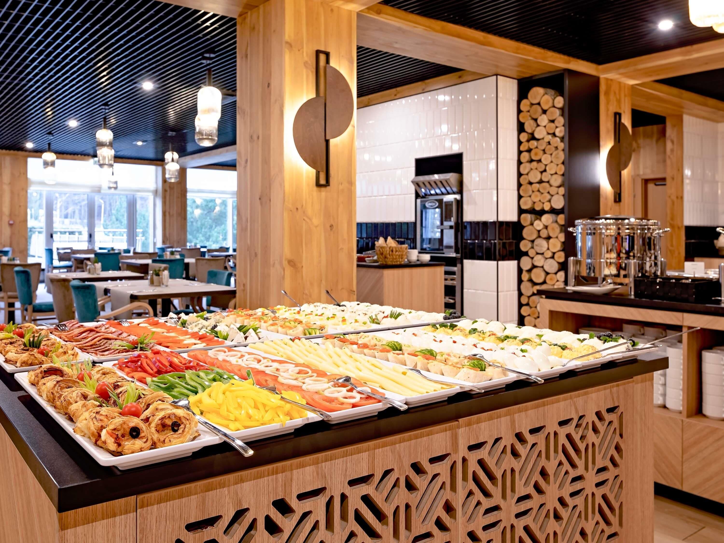 A buffet with various food items, wooden paneling, and a modern kitchen in the background.