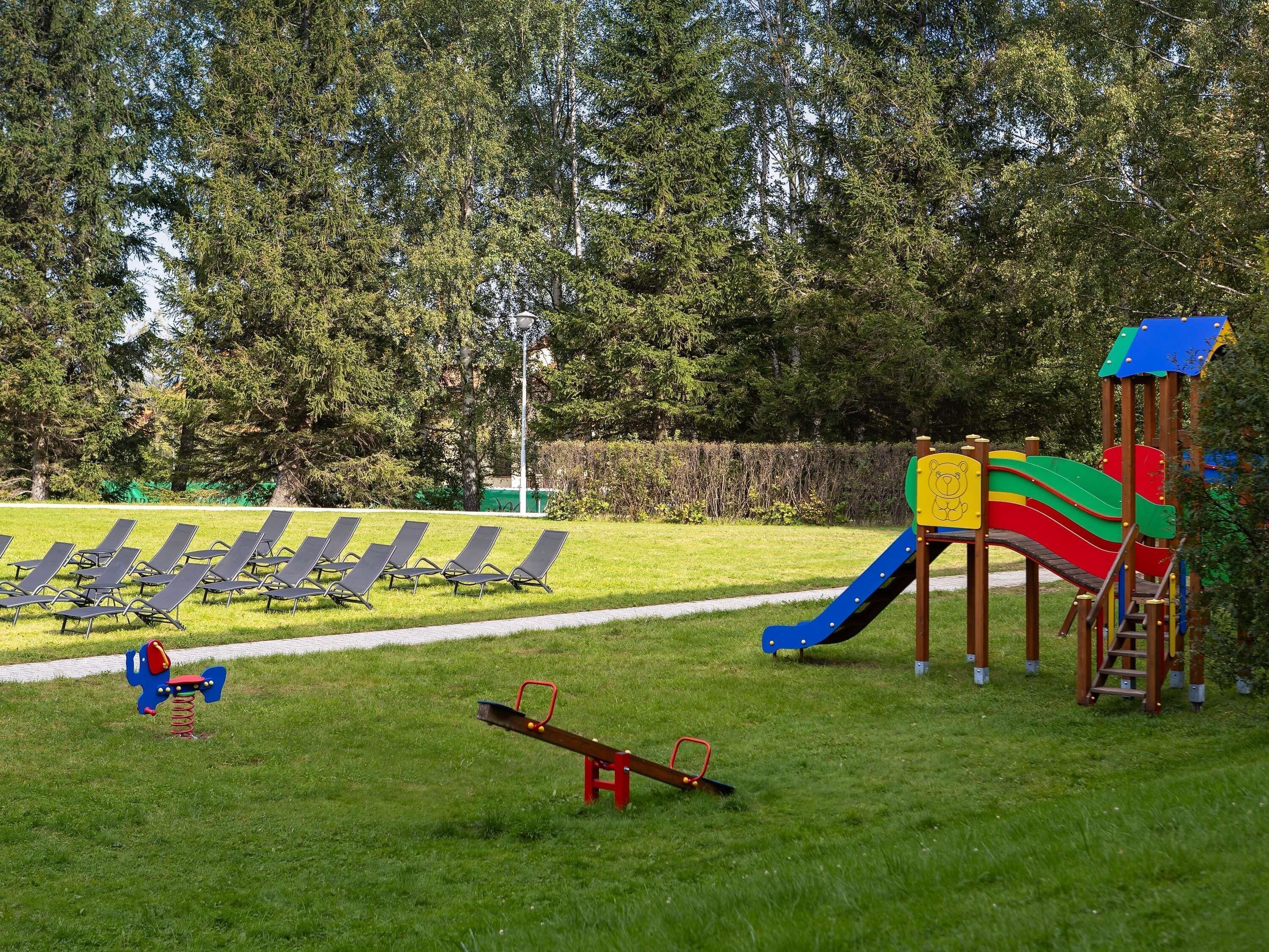 A playground with a slide, swings, and a seesaw.