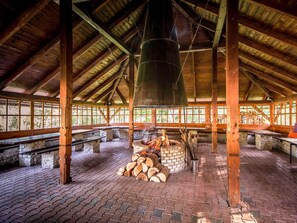 A covered wooden pavilion with stone benches, a central fire pit, and a hanging lantern. - Mercure Karpacz Skalny (Karpacz)