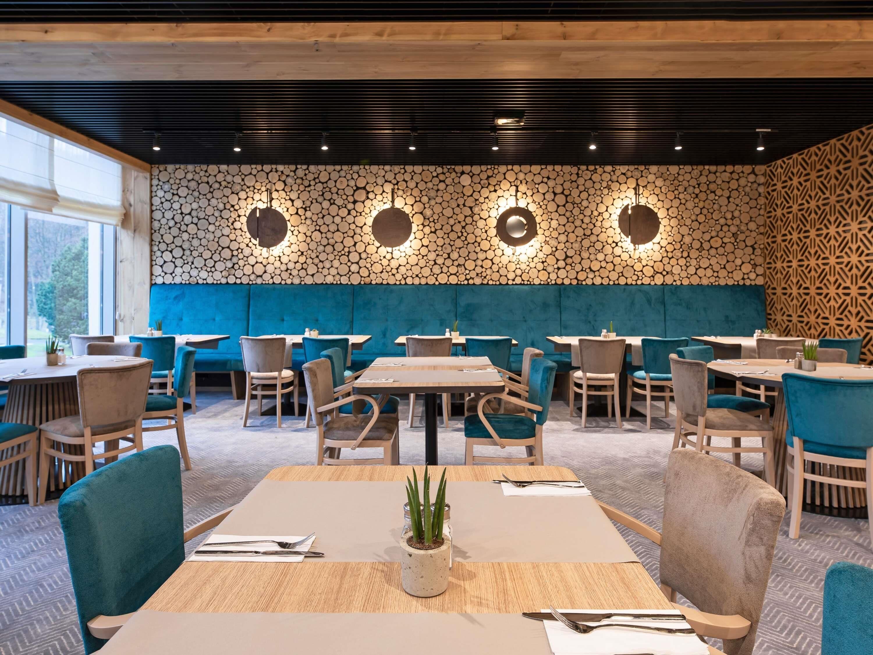 Ein Restaurant mit Holzwänden, blauen Sitzmöglichkeiten und gedeckten Tischen.