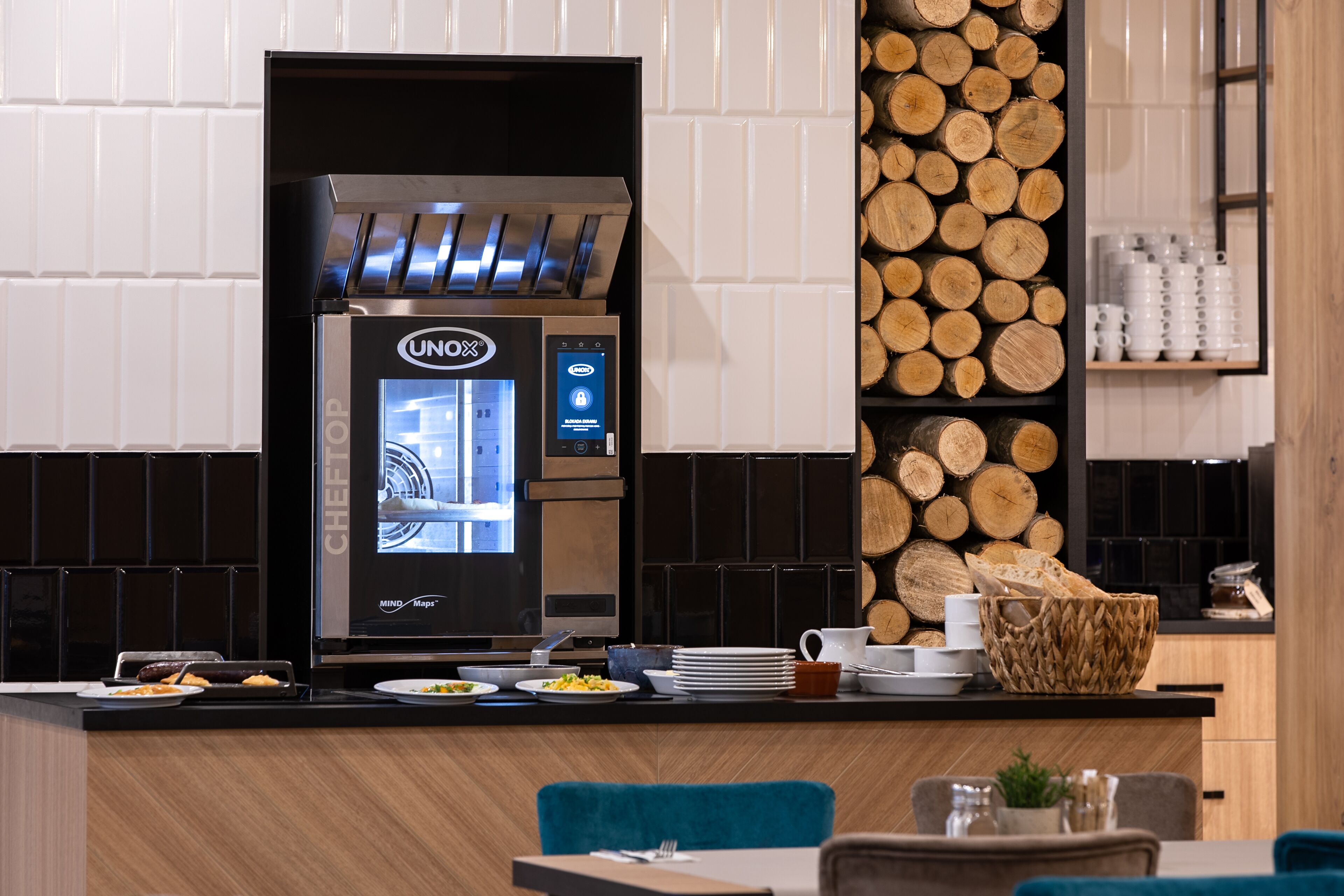 A modern kitchen with a built-in coffee machine, wooden log display, and a breakfast bar.