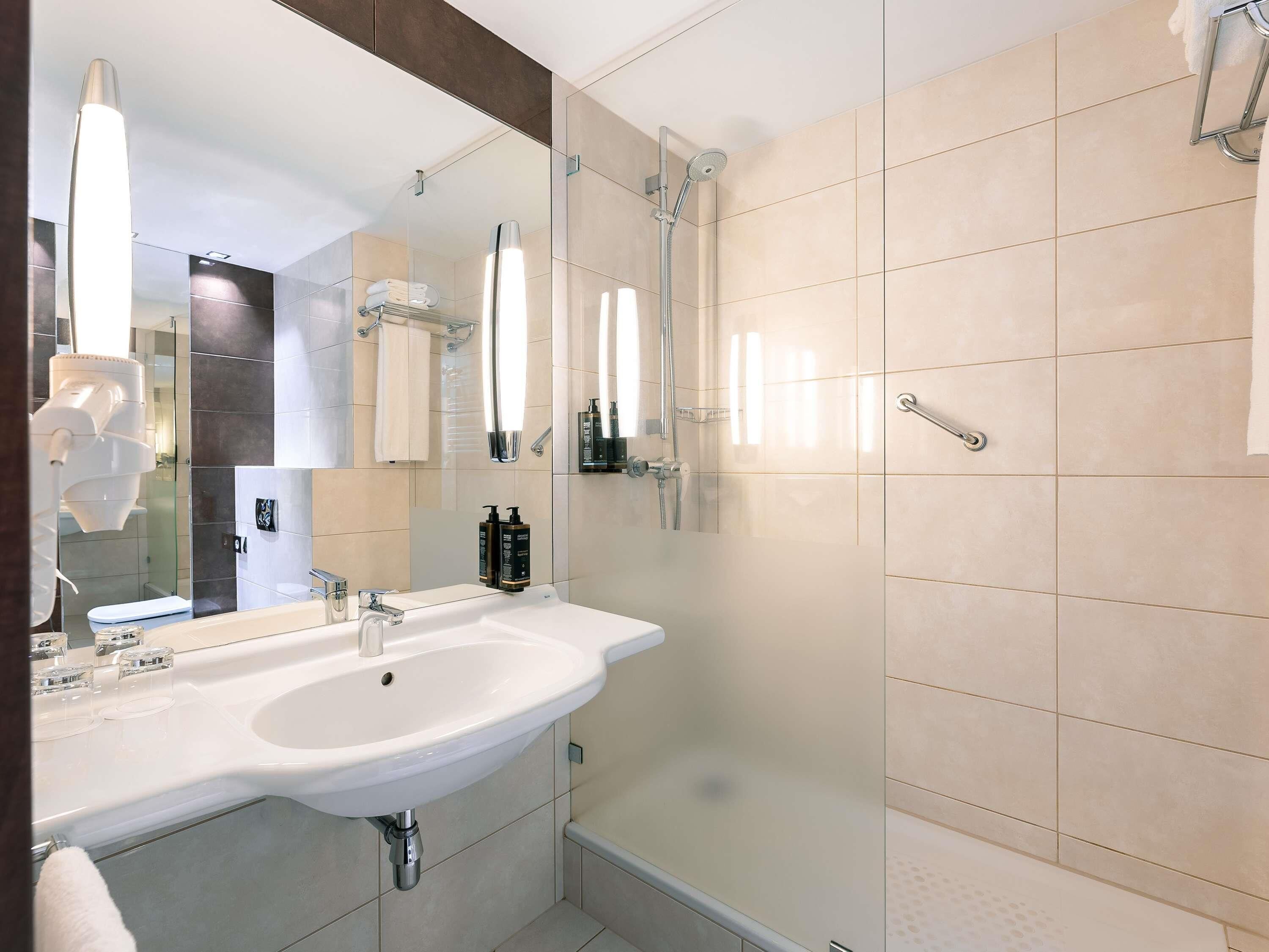 A modern bathroom with a large sink, mirror, and shower.