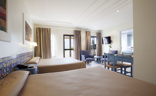 A hotel room with two beds, a desk with a chair, a TV, and a window with curtains.