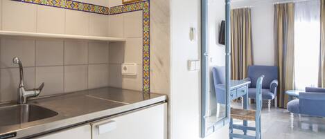 Une cuisine moderne équipée d’un évier, d’un plan de travail et de placards. On y trouve également un coin repas avec une chaise et une table.
