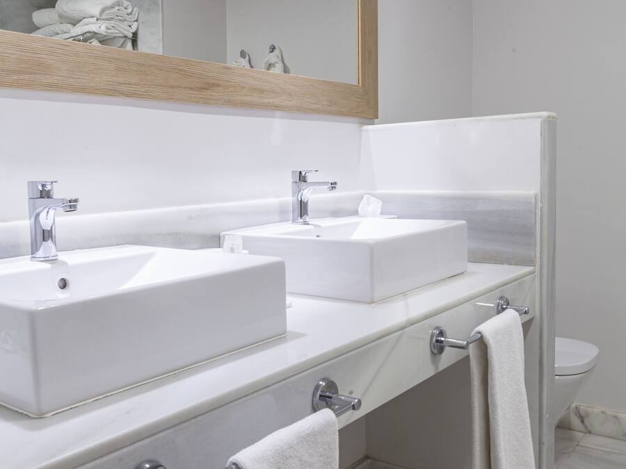 Un bagno moderno con due lavabi, uno specchio e un water.