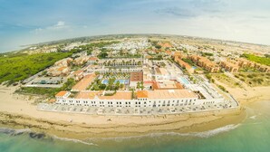 Vista aérea de un resort costero con un edificio central rodeado de playa y océano.