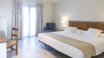Una habitación de hotel con una cama grande, una silla de madera, un escritorio y una lámpara.