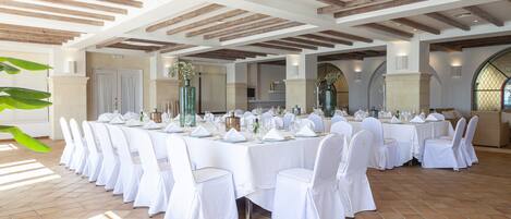 A banquet hall with white tablecloths, round tables, and white chairs.