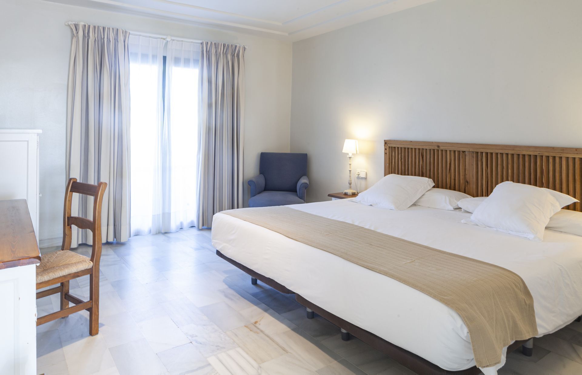 Une chambre d’hôtel avec un lit, une chaise, un bureau et une lampe.