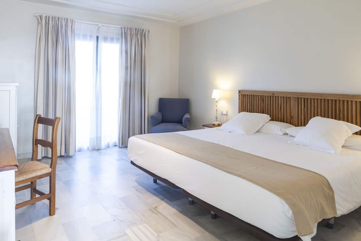 Ein Hotelzimmer mit Bett, Stuhl, Schreibtisch und Lampe.