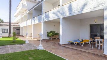 Un edificio de varios pisos con un patio cubierto que cuenta con mesas al aire libre y un pequeño jardín.