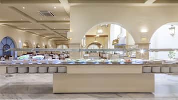 Un espace buffet doté de plusieurs présentoirs de nourriture, d’un sol en marbre et d’un plafond haut avec des luminaires encastrés.