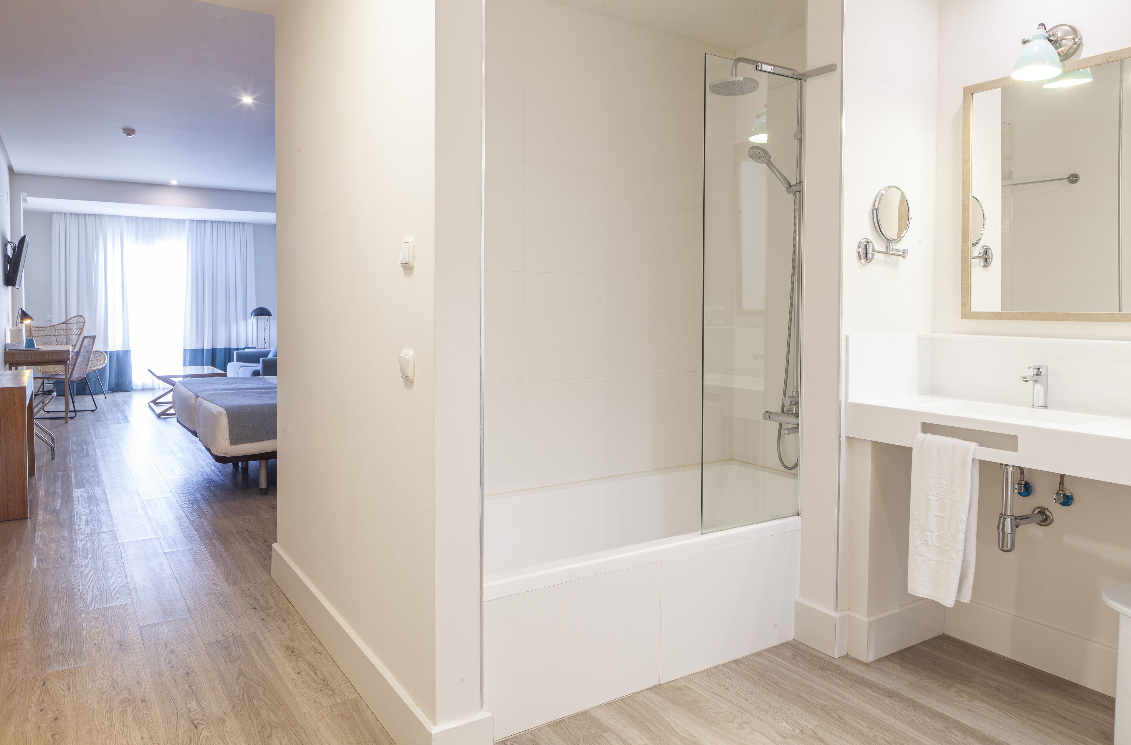 A modern bathroom with a glass-enclosed shower, a bathtub, and a vanity with a mirror.