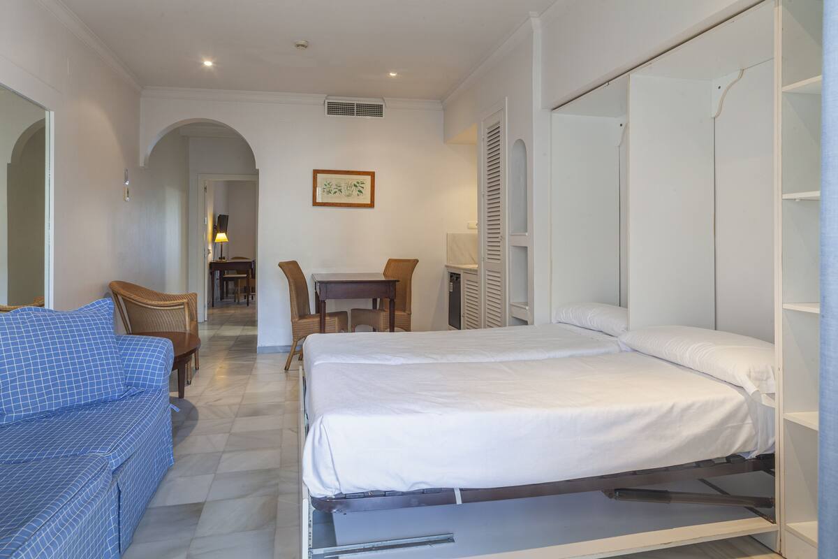 Une chambre à coucher avec un lit, un canapé, une table et des chaises.