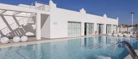 Un hôtel moderne doté d’une piscine, d’un escalier et d’un panneau indiquant un espace de détente.