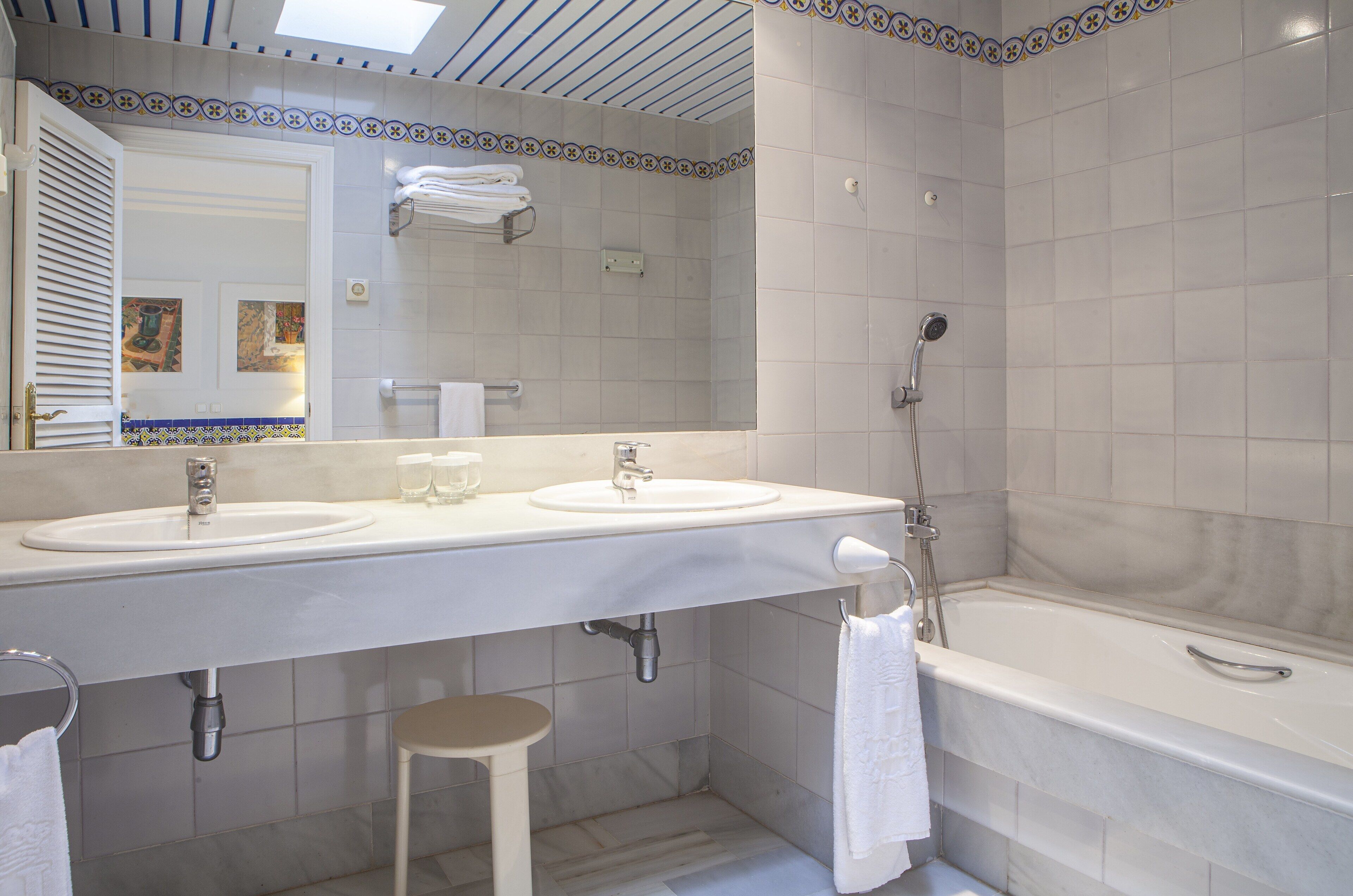 Une salle de bain avec deux lavabos, un grand miroir, une douche et des toilettes.