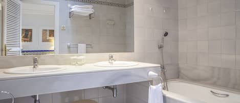 Een badkamer met twee wasbakken, een grote spiegel, een douche en een toilet.