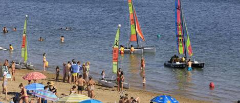 Une plage avec des gens, des bateaux et des parasols.