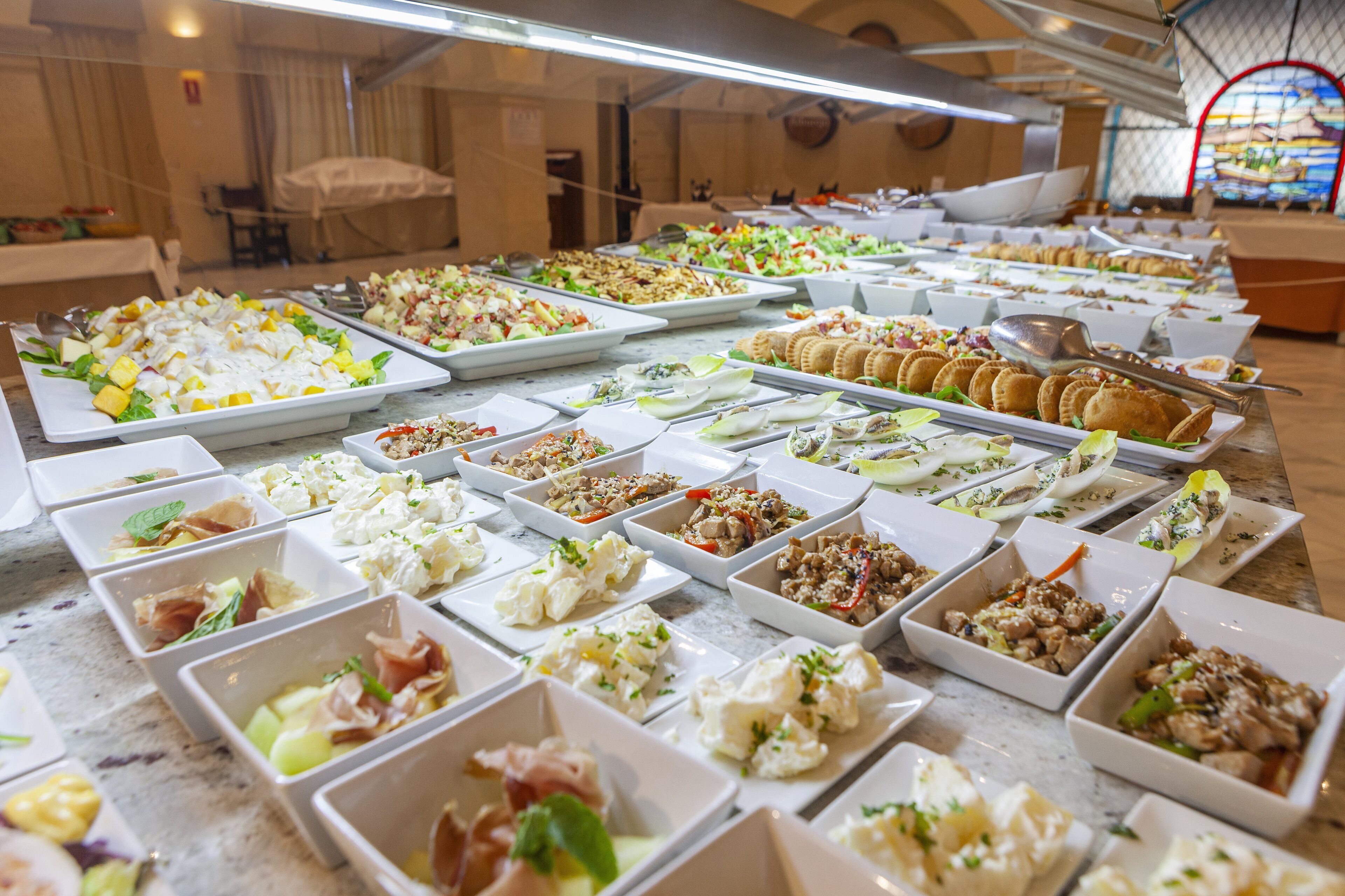 A buffet with various dishes including salads, meats, and pastries.