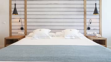 A double bed with a blue throw blanket, two bedside tables with lamps, and a wooden headboard.
