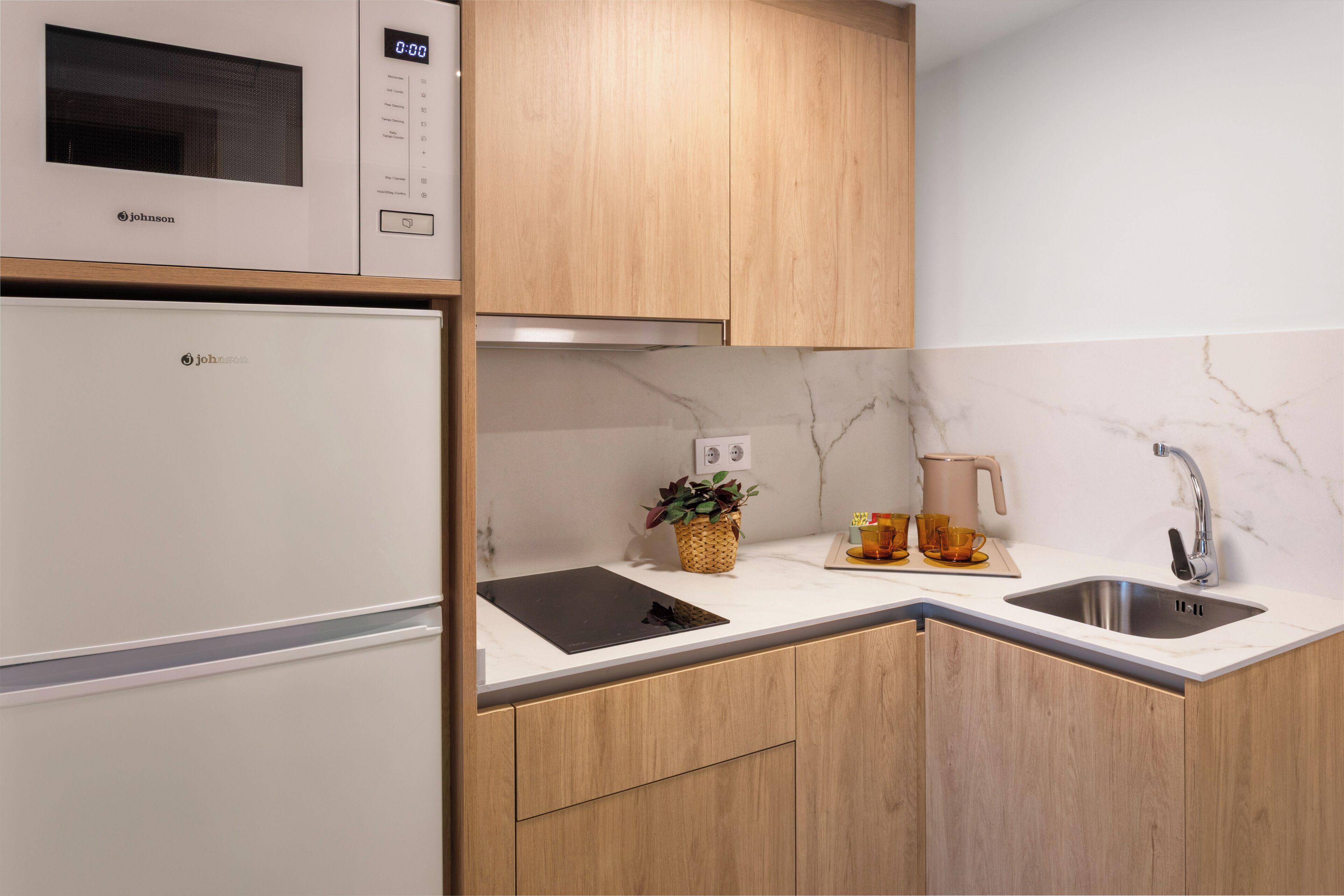 Una cocina equipada con microondas, cafetera y lavabo.