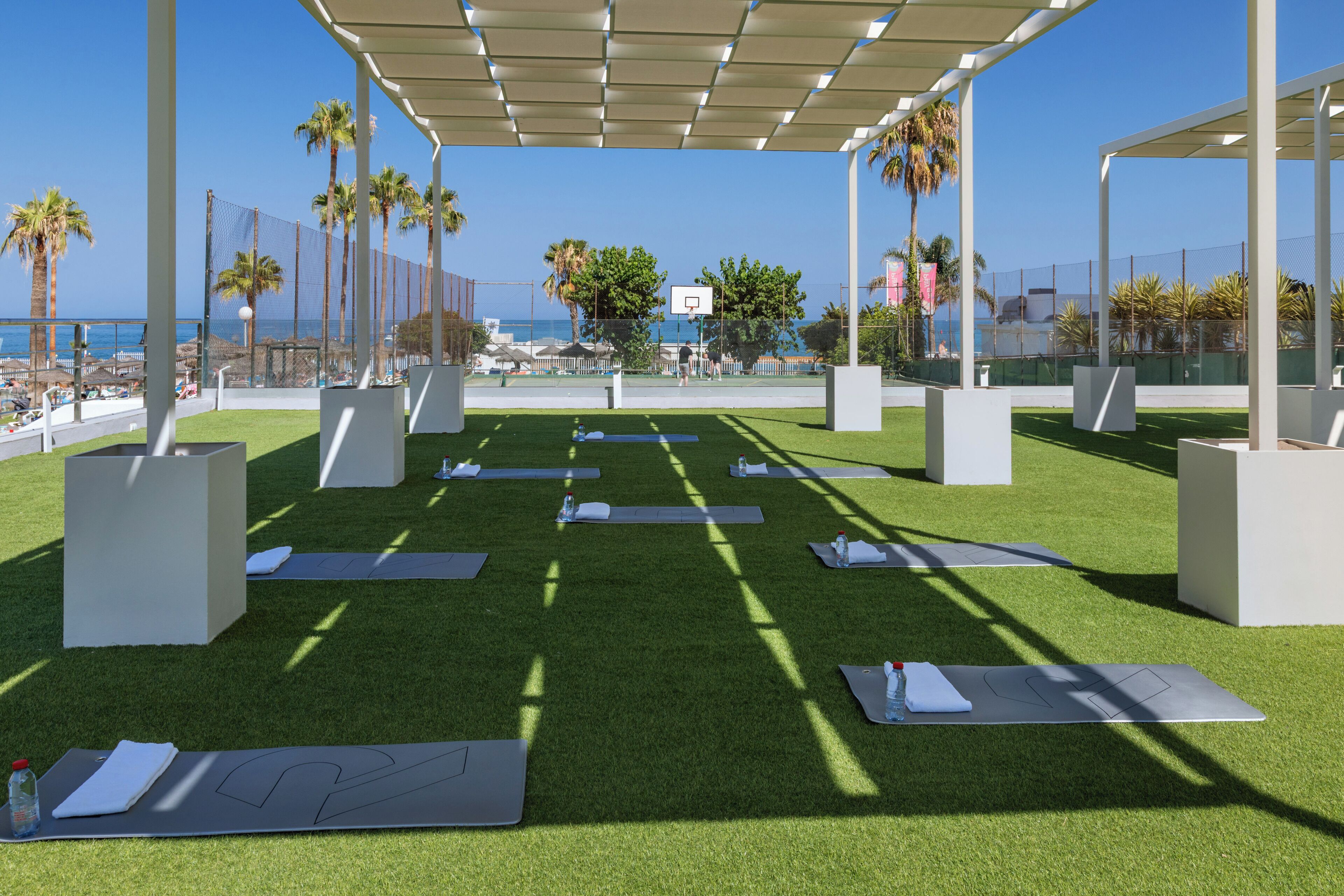 An outdoor exercise area with artificial grass, yoga mats, and exercise equipment.