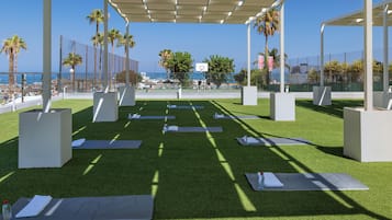 An outdoor exercise area with artificial grass, yoga mats, and exercise equipment.
