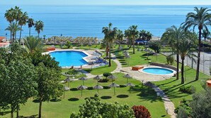Un complexe hôtelier doté d’une grande piscine, d’une plus petite piscine circulaire et de palmiers.