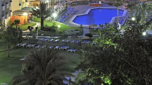 Un hôtel de grande hauteur doté d’une piscine, de palmiers et offrant une vue sur l’océan.