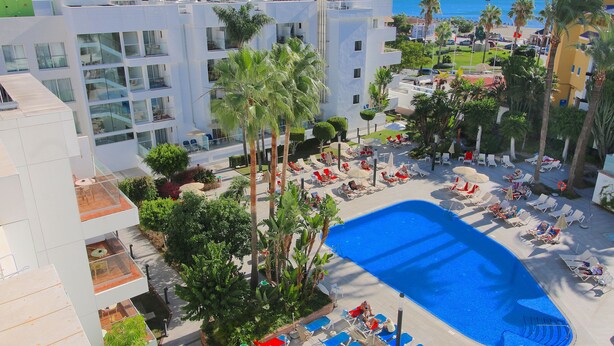 Ein Hotel mit Poolbereich, Palmen und Meerblick.