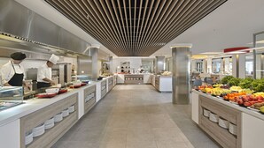 Eine moderne Küche mit Köchen, die Speisen zubereiten, einer zentralen Kochinsel mit Obst und einem klaren, zeitgemäßen Design.