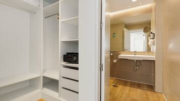 Een moderne badkamer met een grote spiegel, een wastafel en een toilet. Er is een wit meubelstuk met lades en planken.