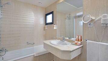Un baño moderno con bañera, lavamanos, espejo y secador de pelo.