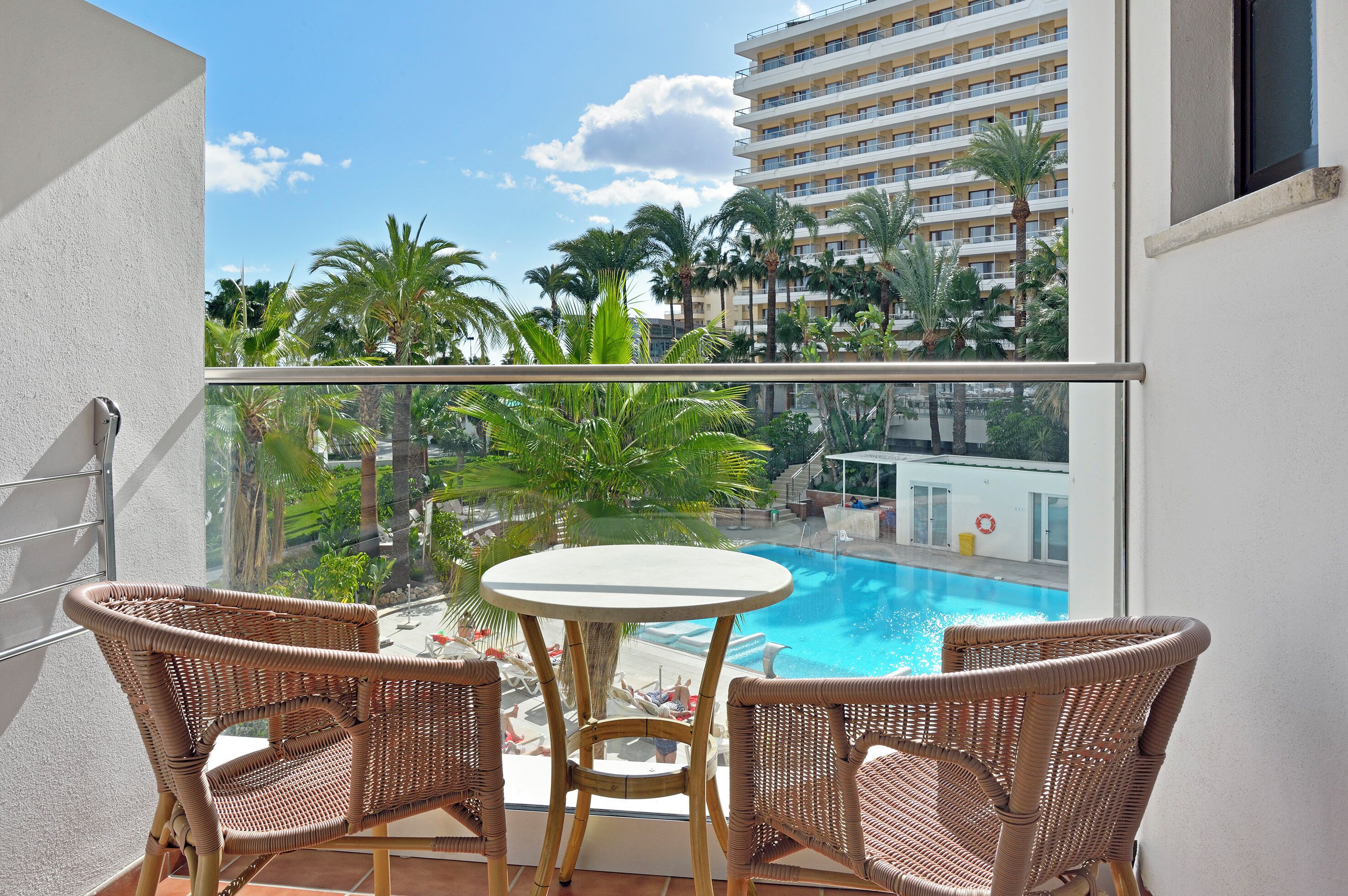 Varanda com piscina, móveis de vime e vista para um edifício de hotel.