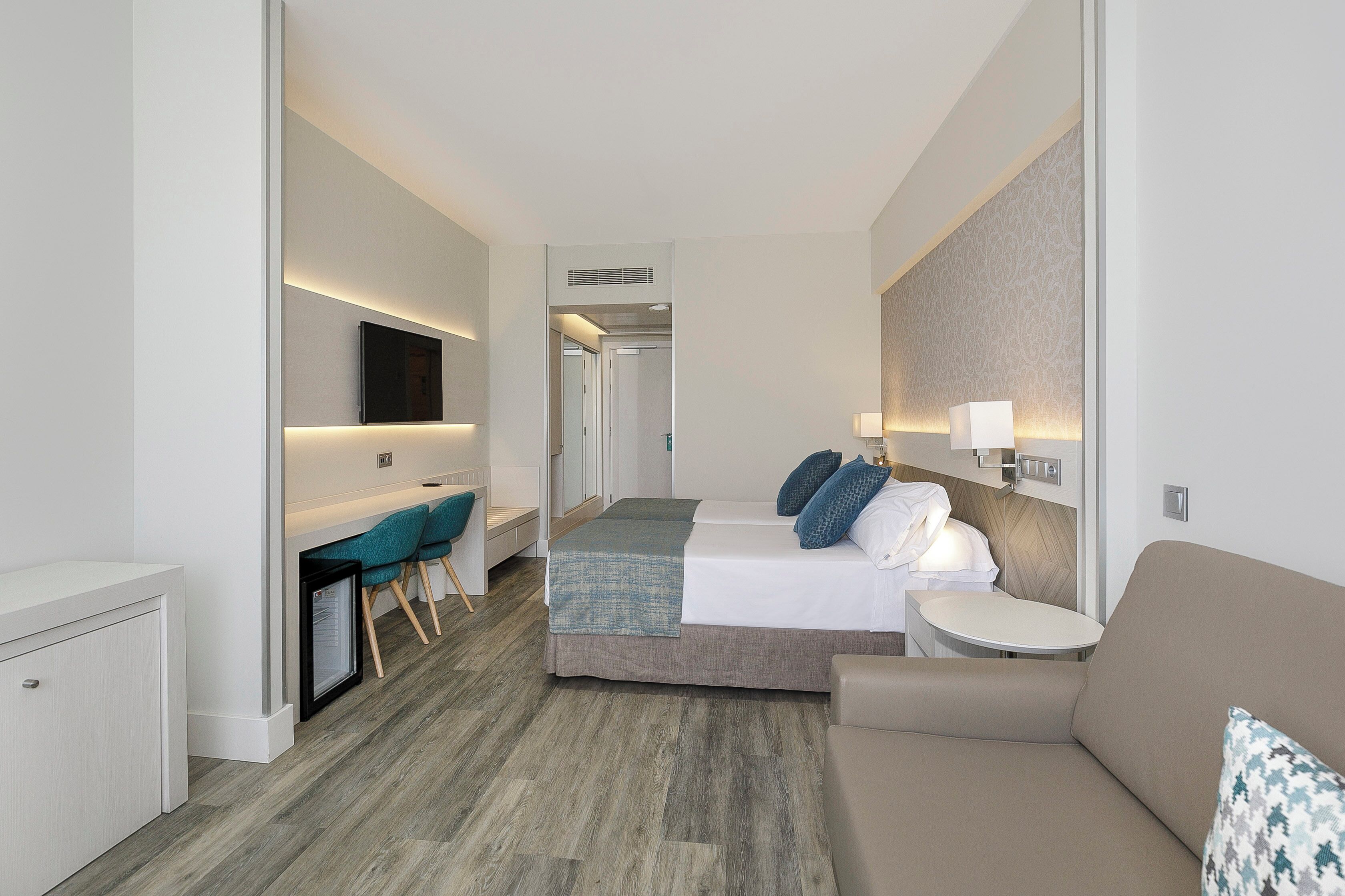 Een moderne hotelkamer met een bed, bureau, stoel, bank en televisie.