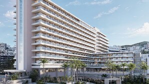 Un hotel moderno con varios balcones, un letrero llamativo y un patio ajardinado.