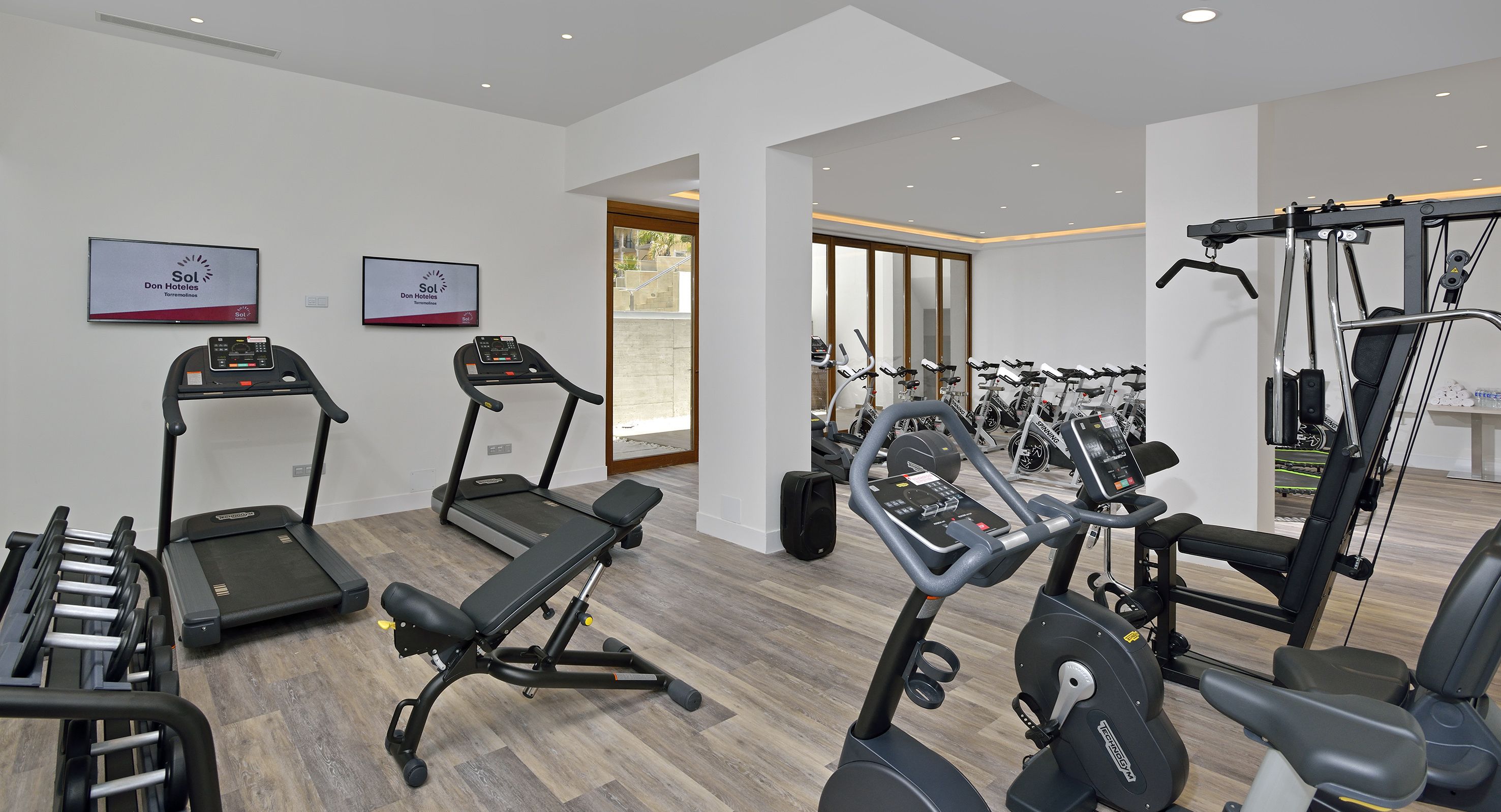 A modern gym with treadmills, elliptical machines, and free weights.