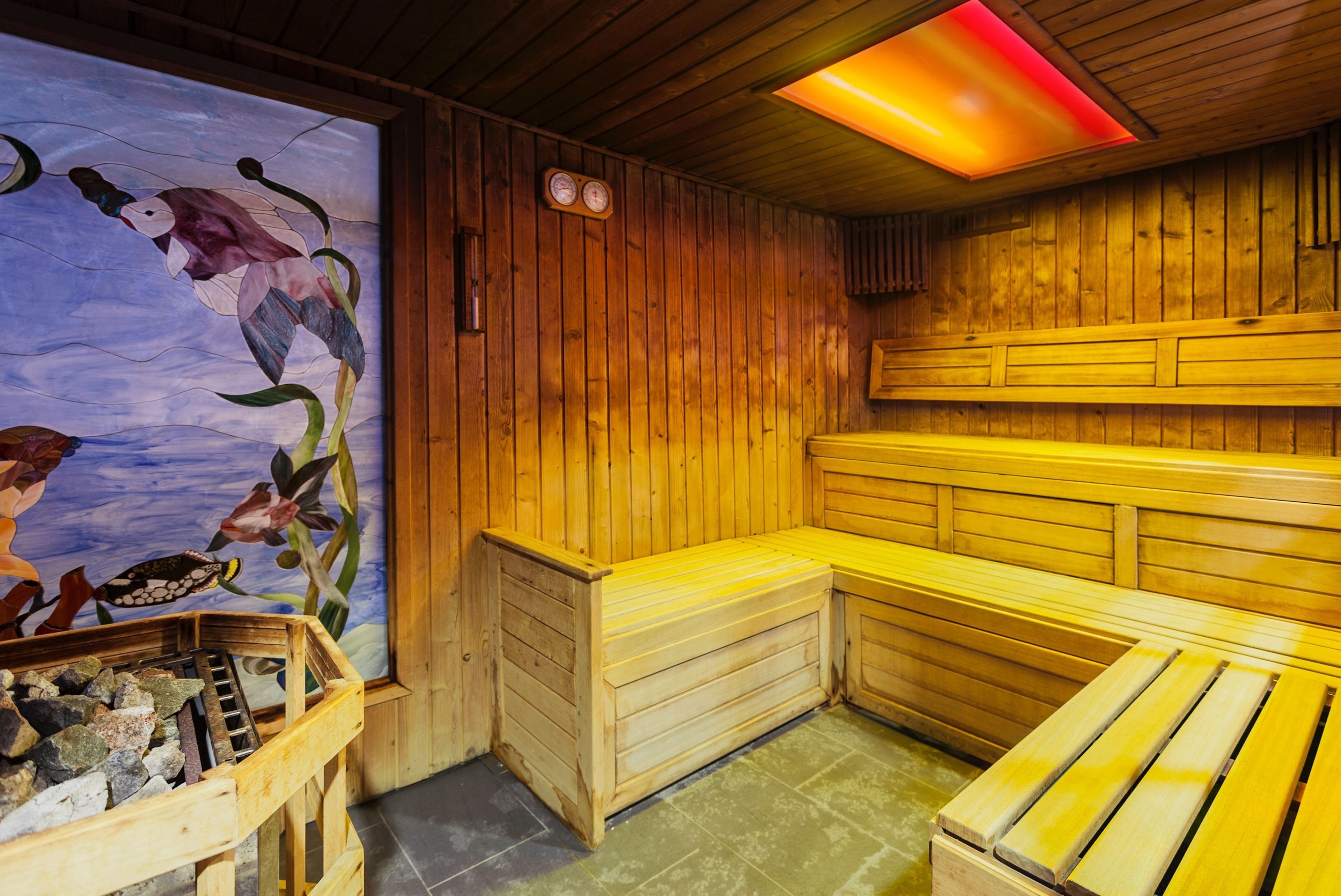A wooden sauna with benches and a mural of fish.