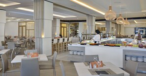 Un restaurante moderno con una barra central, varias mesas para comer y un mostrador para buffet.