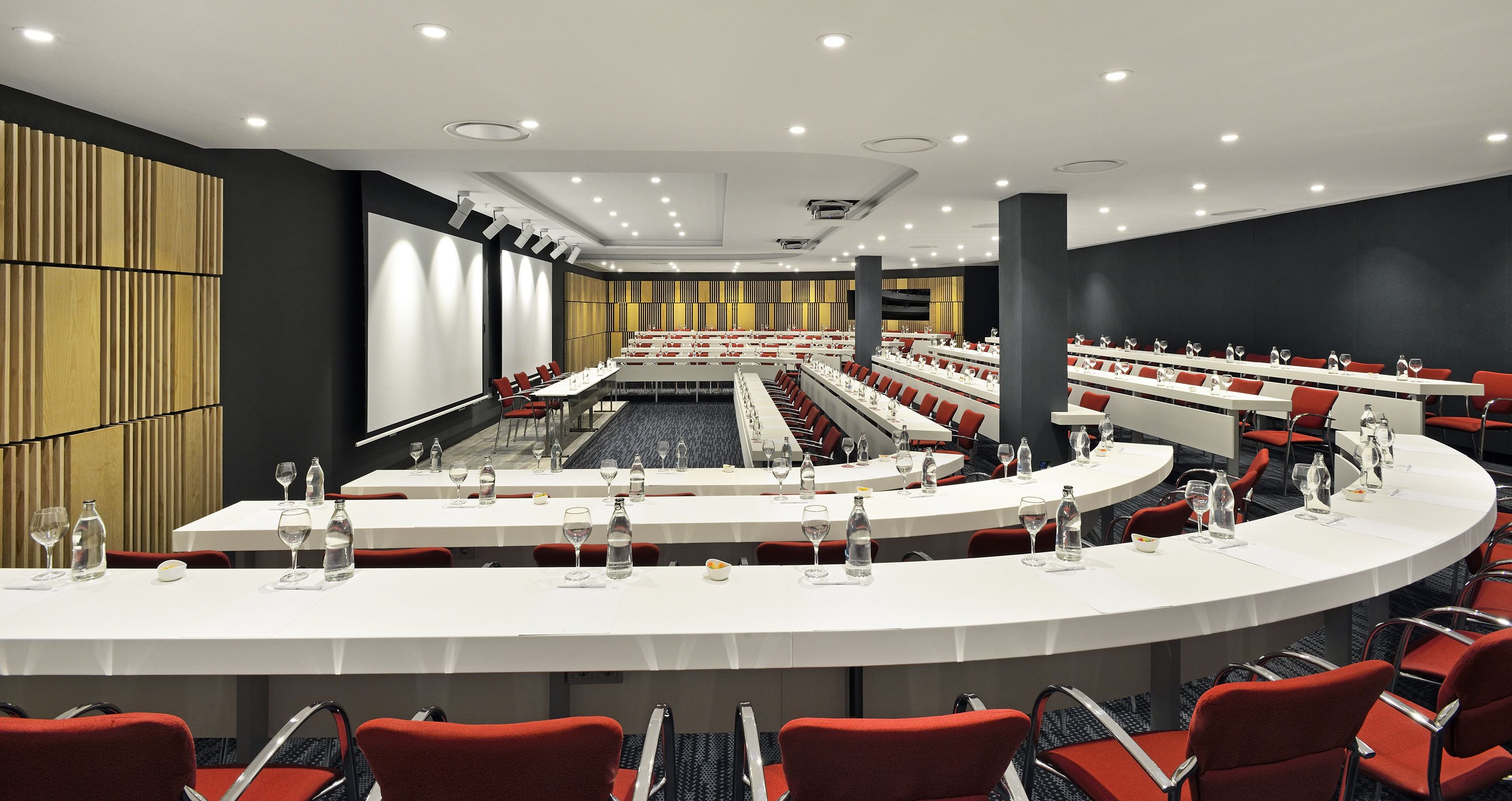 A conference room with multiple tables and chairs, equipped with water bottles and glasses.