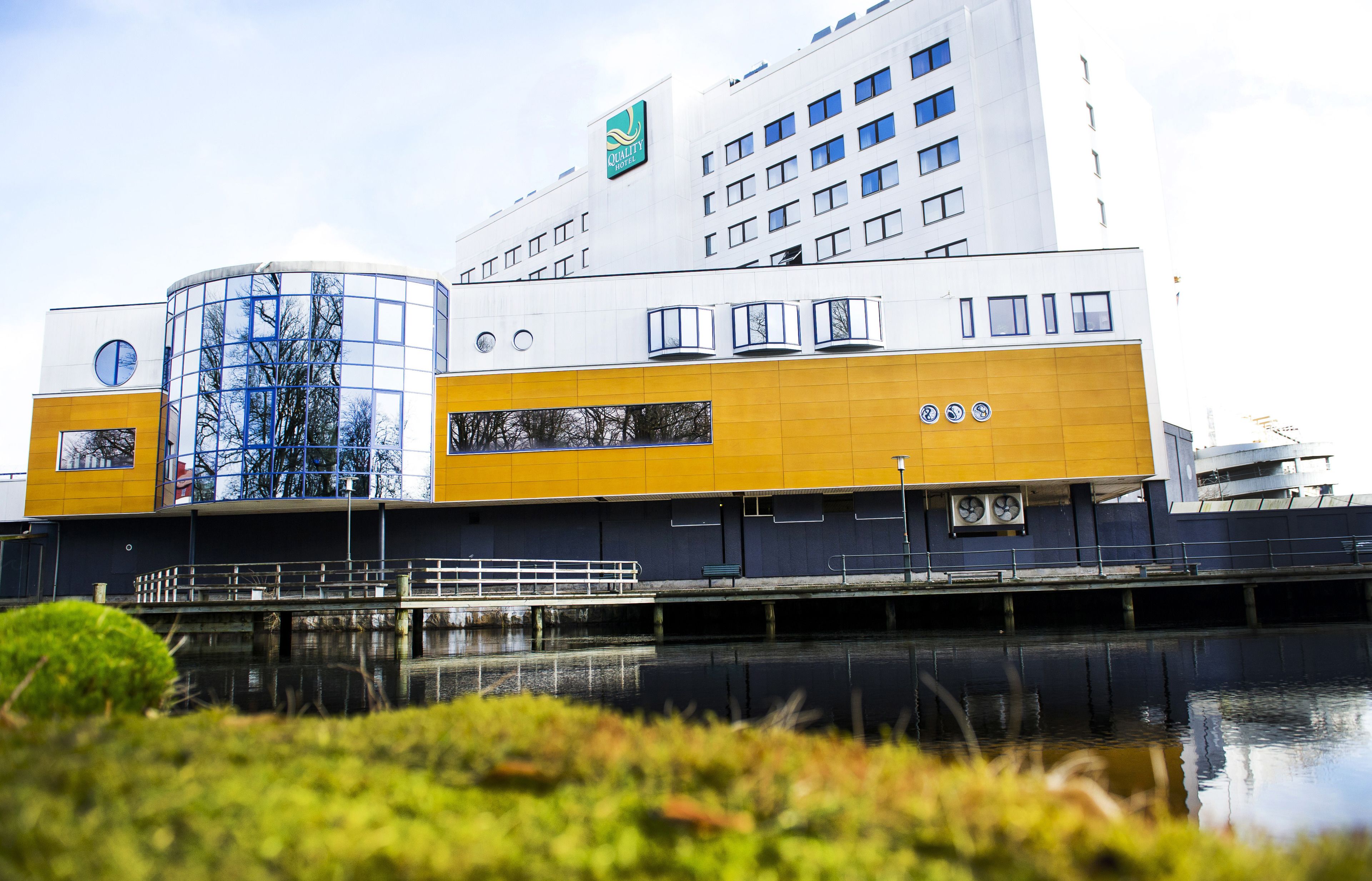 Ein modernes Hotel mit einer markanten, gelb-weißen Fassade, einem Glasbereich und einer Lage am Wasser.