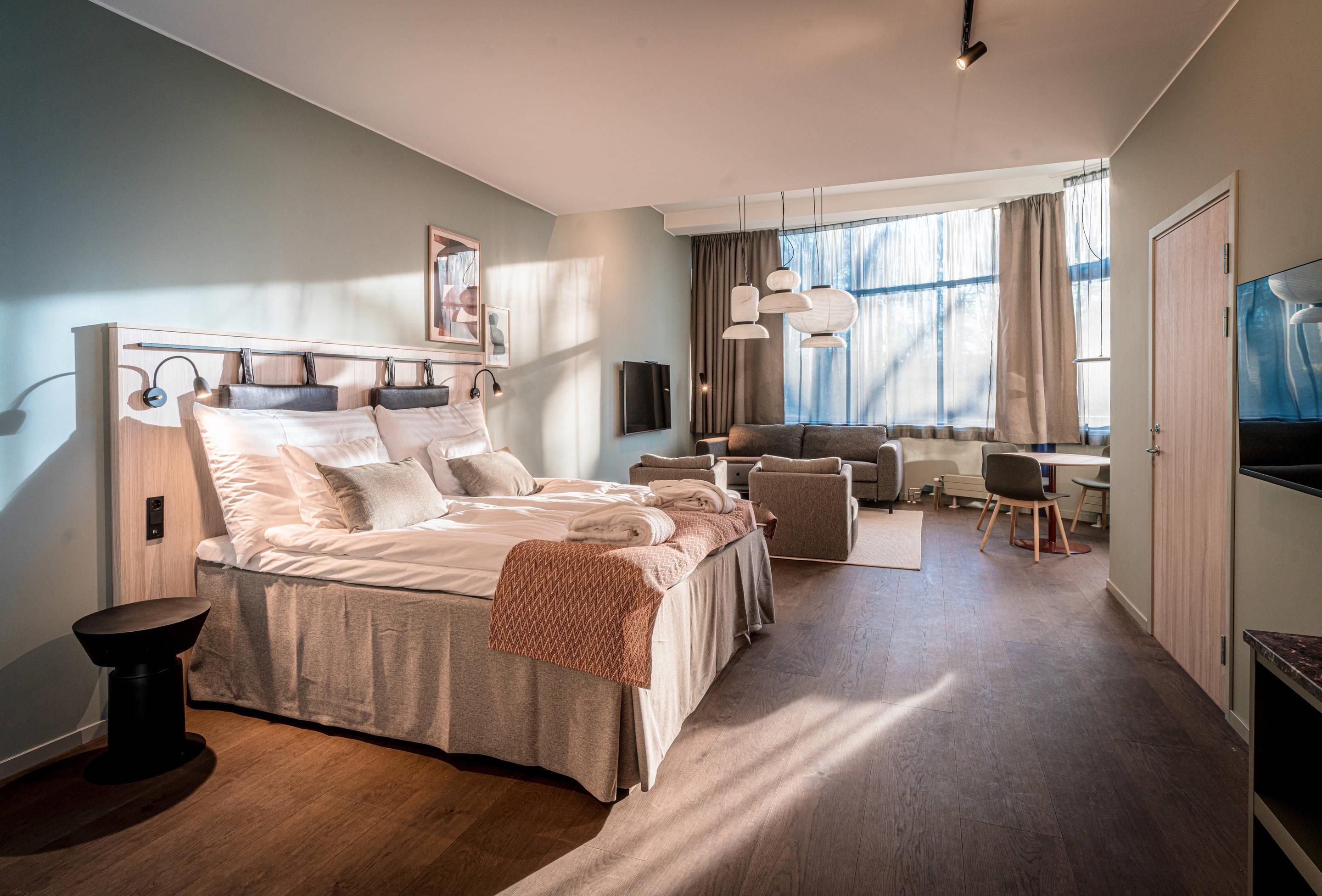 Ein modernes Hotelzimmer mit einem großen Bett, einem Schreibtisch und einer Sitzecke.