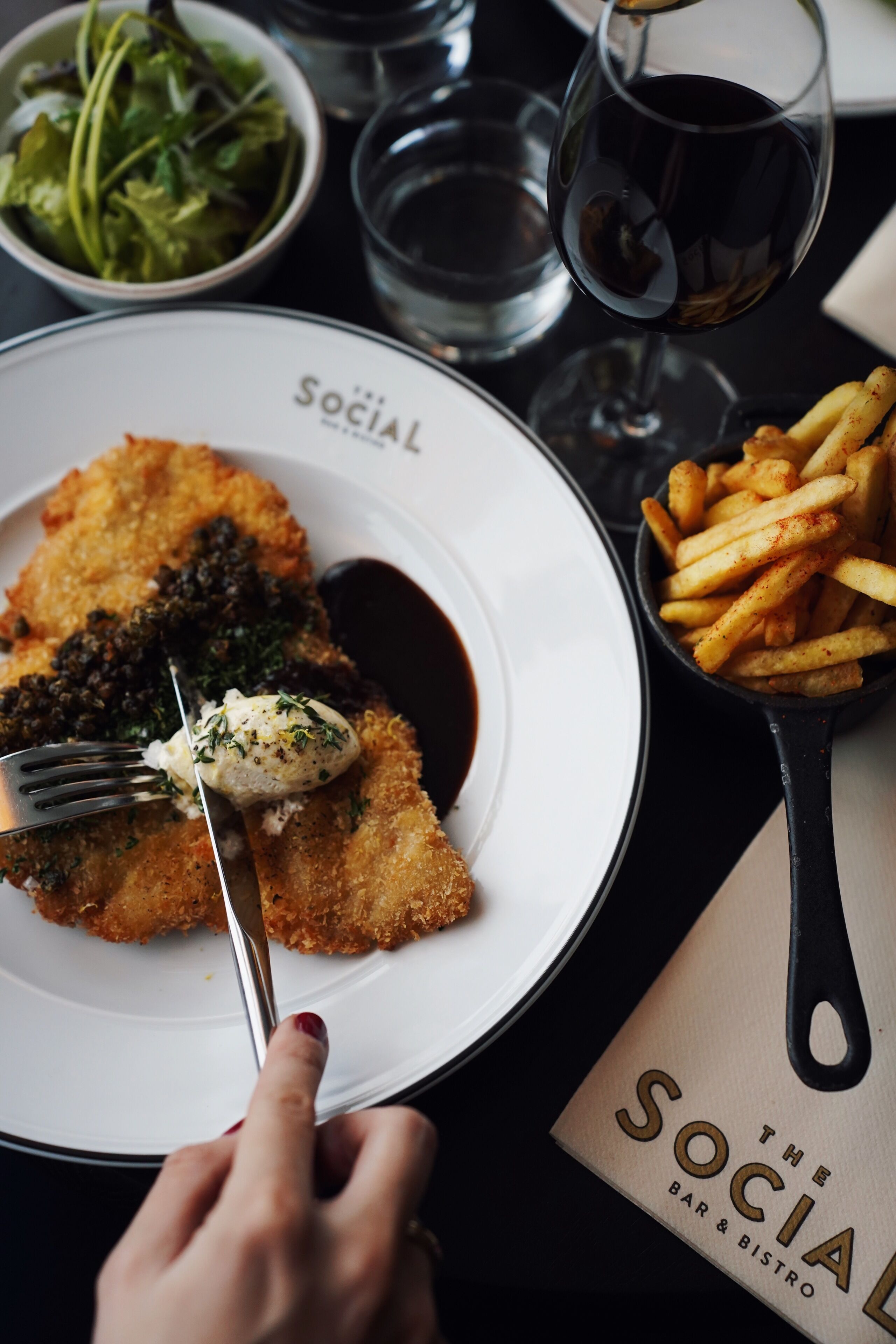 A dining table with a plate of food, a fork, and a menu.