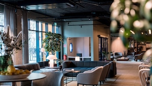 A modern lounge area with sofas, tables, and a large potted plant. - Quality Hotel Grand Boras (Borås)